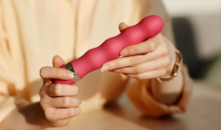 Une femme tient un gode à la main