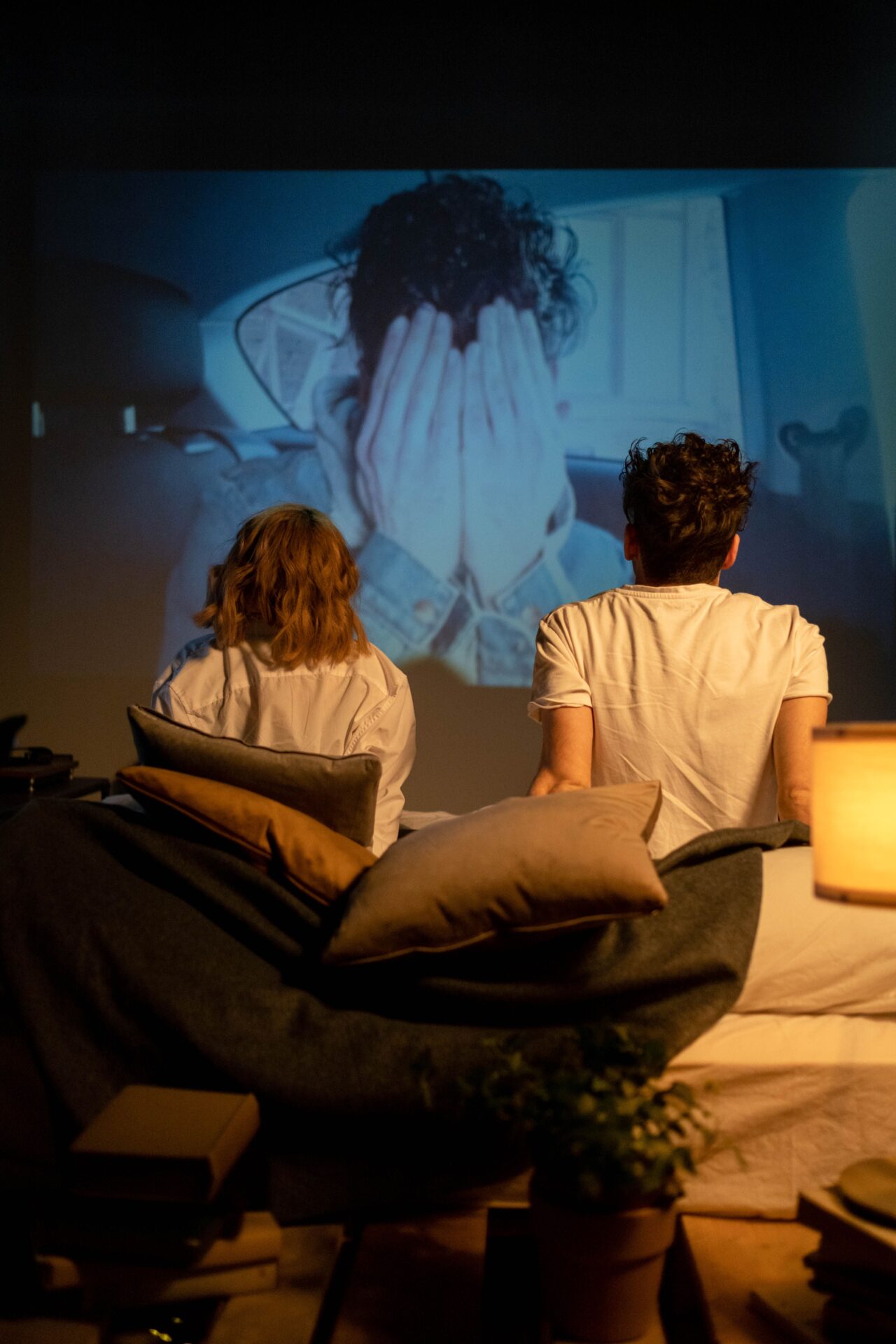 Un couple assis de dos regarde ensemble une image projetée sur le mur
